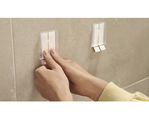 Iemand bevestigt een zelfklevende haak aan een muur