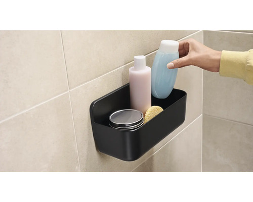 Zwarte douche-organizer met verzorgingsproducten aan de wand