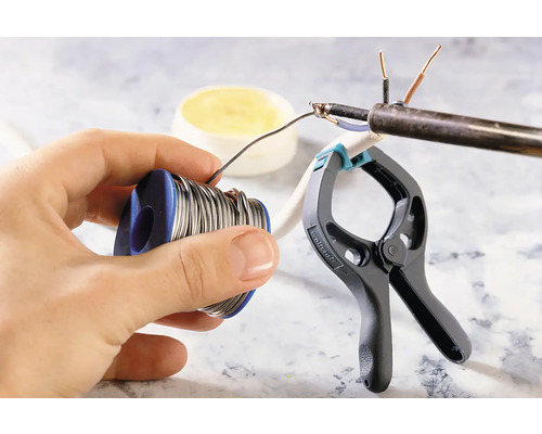 Solderen van een elektrische leiding met soldeertin, soldeervet en een klem.