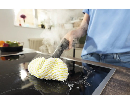 Een persoon reinigt een kookplaat met een stoomreiniger.