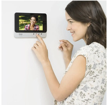 Vrouw bedient Philips deurintercom aan de muur