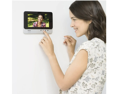 Vrouw bedient Philips deurintercom aan de muur