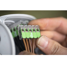 Detailopname van een man die elektrische leidingen verbindt met een Wago 221-klem
