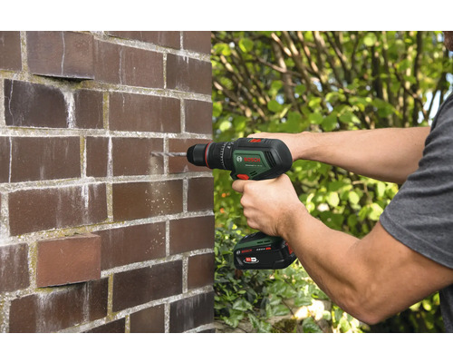 Man boort gat in bakstenen muur met accuboormachine