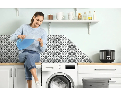 Vrouw zit op wasmachine en giet vloeistof uit kan in maatbeker