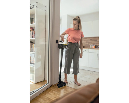 Vrouw gebruikt draadloze stofzuiger in de woonkamer