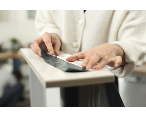 Iemand brengt een zelfklevende folie aan op een oppervlak.