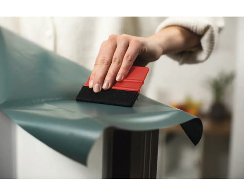 Persoon strijkt plakfolie glad met een rakel