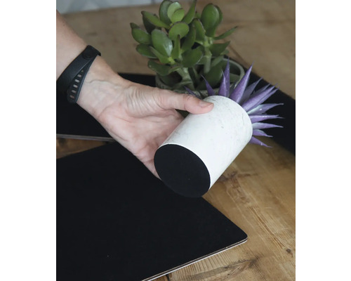 Decoratieve opstelling met kunstplant in witte pot en zwart tafelkleed.