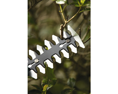 Close-up van een heggenschaar die een tak afsnijdt.