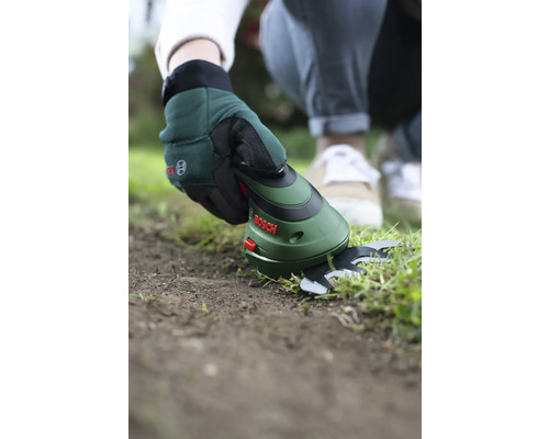 Een persoon gebruikt een Bosch accu grasschaar om gazonranden te knippen.