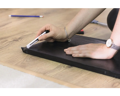 Persoon snijdt plint met een stanleymes