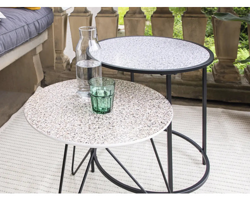 Twee ronde bijzettafels met drankkaraf en glas op een terras