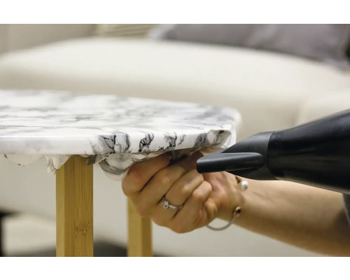 Decoratieve folie wordt met een föhn op een tafel aangebracht