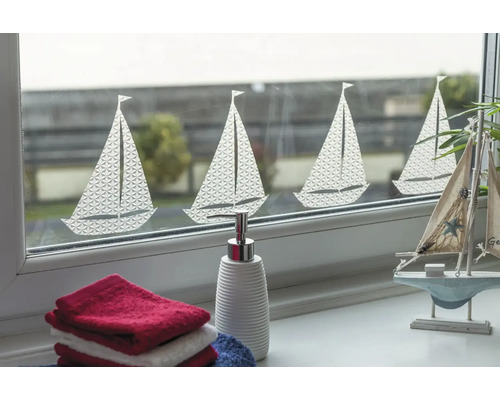Decoratief venster met zeilbootmotief, aangevuld met handdoeken en een zeepdispenser