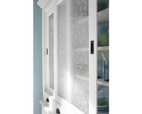 Detailopname van een witte keukenkast met glazen deuren met bloemenpatroon.