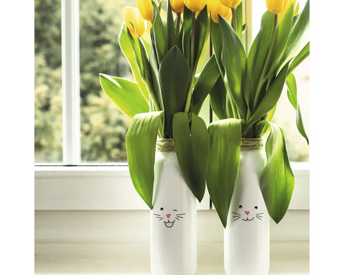 Twee vazen met konijntjesmotieven en gele tulpen op een vensterbank.