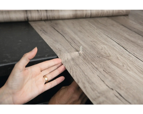 Zelfklevende decoratiefolie met houtlook wordt aangebracht