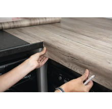 Persoon beplakt werkblad met decoratieve folie in houtlook