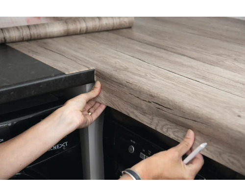 Persoon beplakt werkblad met decoratieve folie in houtlook