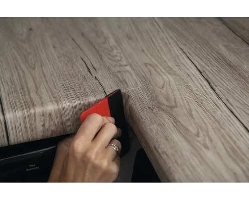 Applicatie van decoratieve folie met een rakel op een houten oppervlak