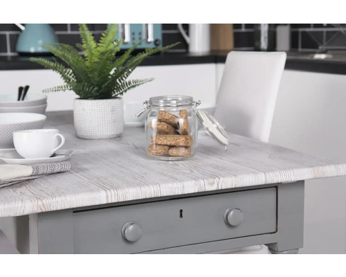 Decoratieve opstelling met tafel, servies en voorraadpot in een keuken.