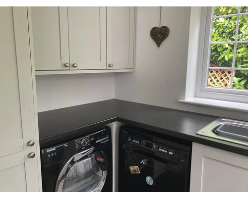 Lichte bijkeuken met wasmachine, droger, vaatwasser, werkblad en wandkast