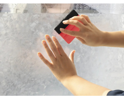 Aanbrengen van decoratiefolie met een rakel op een glazen ruit