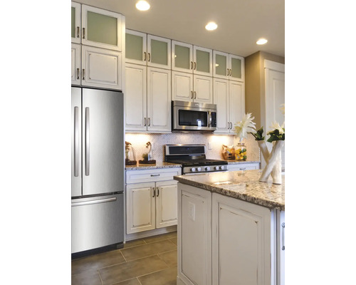 Lichte keuken met roestvrijstalen koelkast, magnetron en kookplaat, evenals een kookeiland en bovenkasten