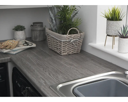 Werkblad met houten structuur, spoelbak en decoratieve elementen zoals planten en manden.