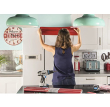 Vrouw bevestigt meubelfolie in een keuken met gereedschap en decoraties.