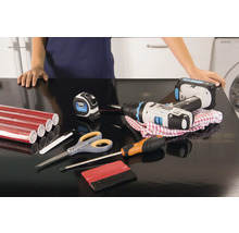 Werkblad met rode meubelfolie, accuschroevendraaier, meetlint, schroevendraaier, schaar en rakel voor montage