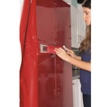 Vrouw brengt decoratieve folie aan op koelkast