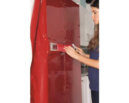 Vrouw brengt decoratieve folie aan op koelkast