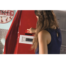 Vrouw brengt met een rakel rode meubelfolie aan op een koelkast.