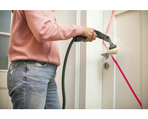 Een persoon reinigt een witte deur met een stoomreiniger.