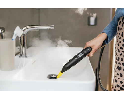 Stoomreiniger in gebruik in een wastafel in de badkamer