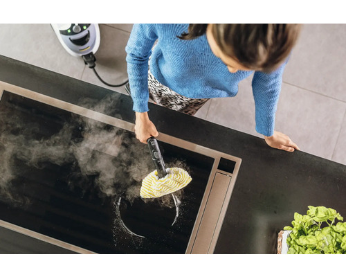 Vrouw reinigt een kookplaat in de keuken met een stoomreiniger.