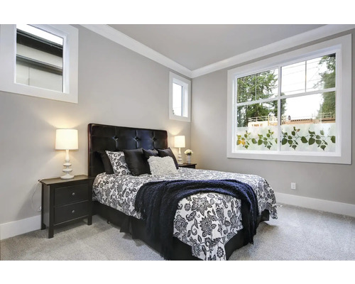 Slaapkamer met bed, nachtkastjes en raam met decoratieve folie