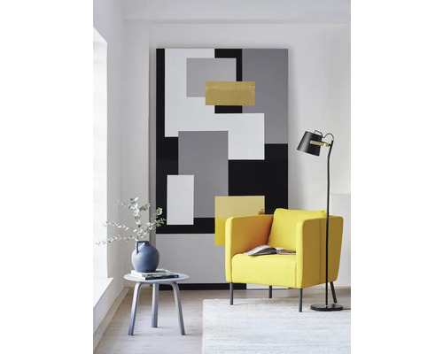 Woonkamer met fauteuil, vloerlamp, bijzettafel en abstracte muurschildering in geometrisch design.