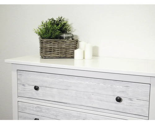 Commode met drie lades, decoratie met planten, kaarsen en een mand