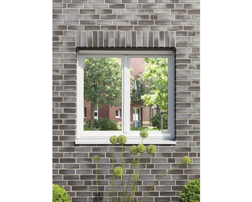 Raam in een bakstenen muur met uitzicht op groen