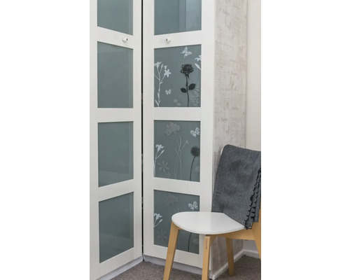 Witte kast met bloemmotieven en glazen deuren naast een stoel met een grijze deken