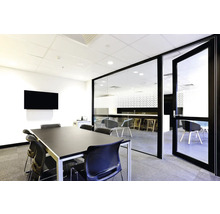 Lichte vergaderruimte met glazen wand, tafel, stoelen en scherm.