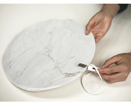 Persoon snijdt folie met marmerpatroon bij met een mes.