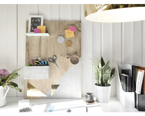 Decoratief memobord met planken, opbergvak en geometrische patronen op een bureau met plant en kantoorartikelen