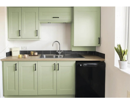 Lichte keuken met spoelbak, kraan, onderkasten, bovenkasten en een zwarte koelkast