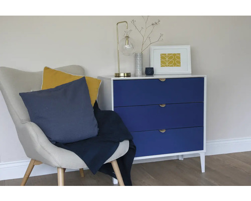 Woonkamerscène met fauteuil, kussens, deken en commode met drie lades