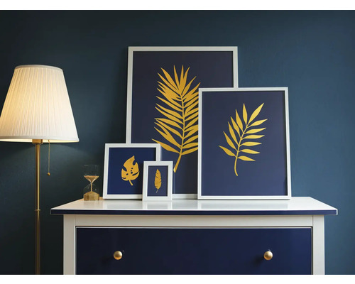 Decoratieve bladerenafbeeldingen in lijsten op dressoir naast staande lamp