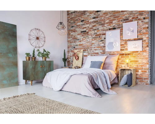 Slaapkamer met bakstenen muur, bed, ladekast, vloerkleed en decoratieve elementen